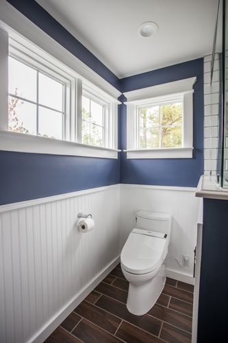 A bathroom with blue walls and white trim and a toilet.