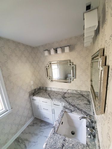 A bathroom with a sink , mirror and cabinets.