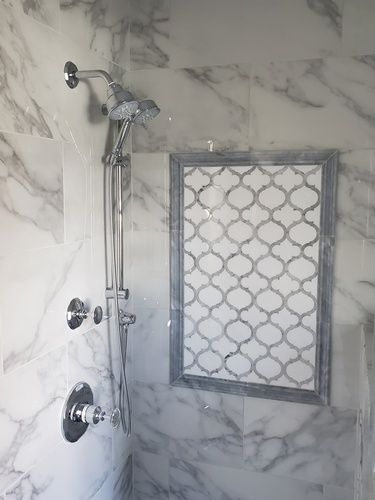 A shower with a shower head and a marble wall.