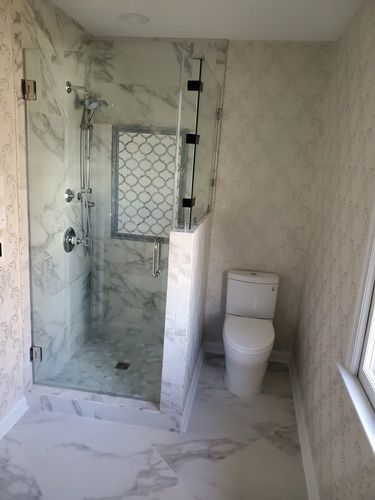 A bathroom with a toilet and a shower with a glass door.