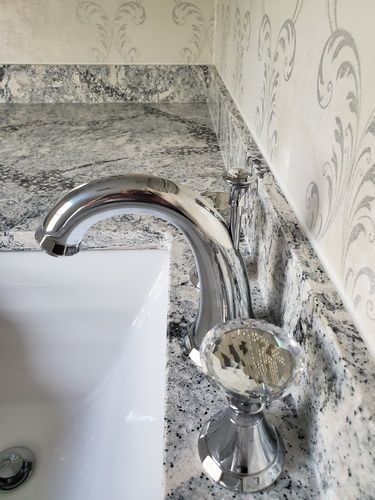 A bathroom sink with a chrome faucet on a granite counter top.