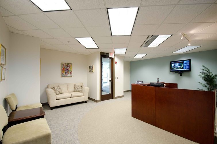 A waiting room with a couch and a television on the wall