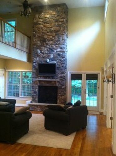A living room with a stone fireplace and a flat screen tv