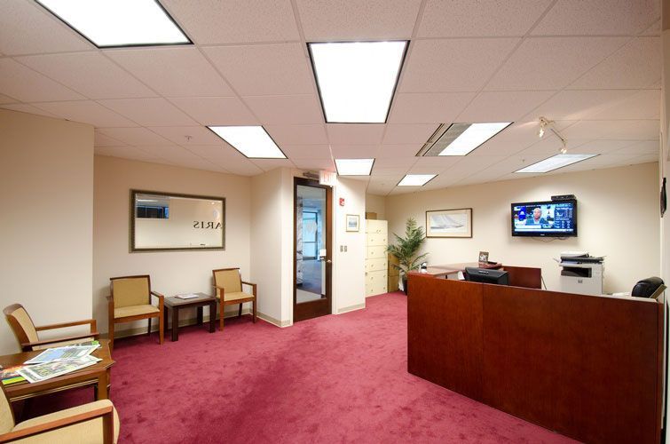 A waiting room with red carpet and a tv on the wall