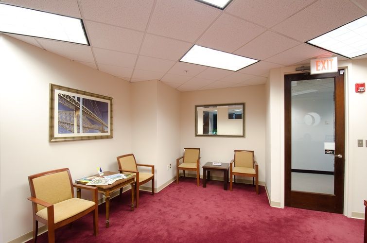 A waiting room with a red carpet and a red exit sign