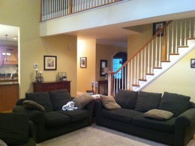 A living room with two black couches and stairs