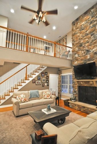 A living room with a couch , coffee table , fireplace and stairs.