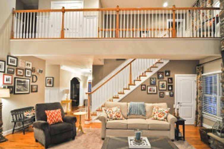 A living room with a couch , chair , coffee table and stairs.