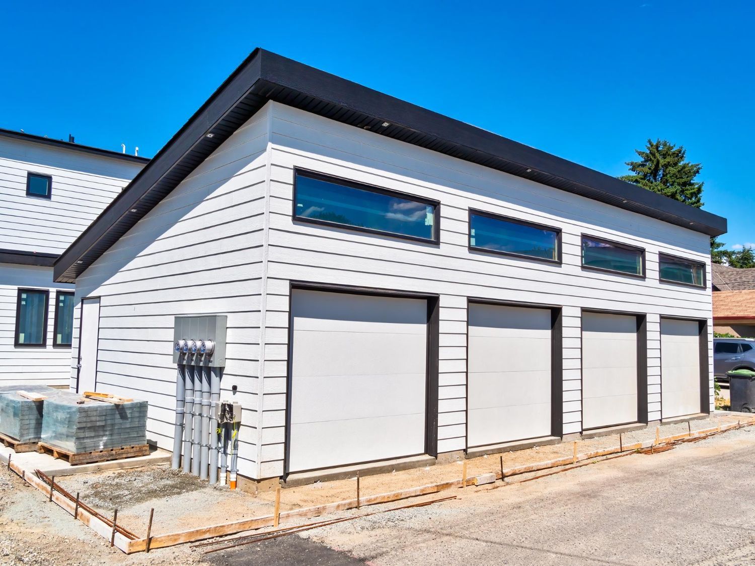 A white garage with a black roof is under construction.