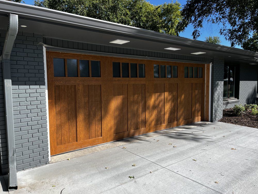 A large wooden garage door is sitting in front of a brick house.