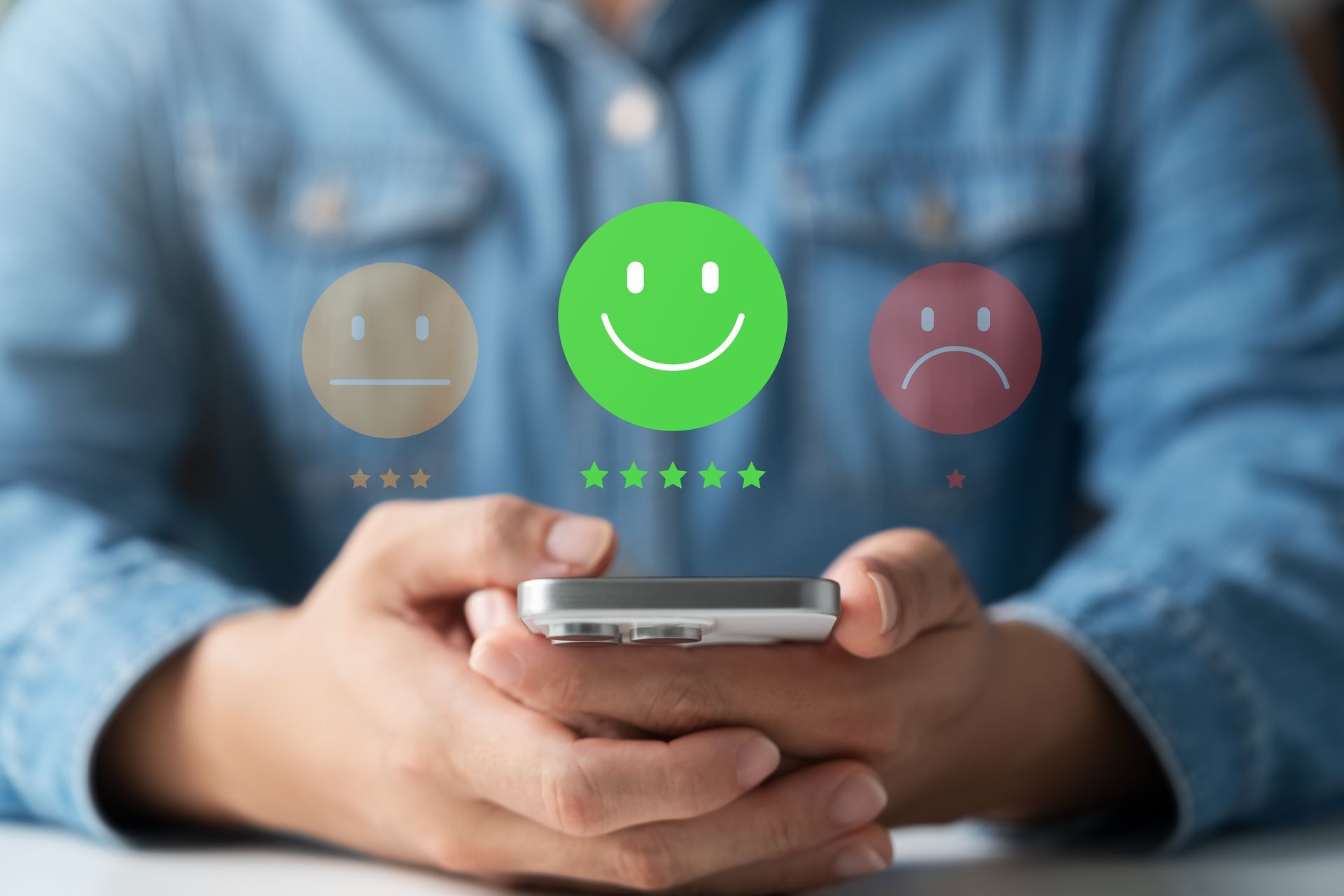 Person holding a smartphone giving a green smiling emoji and five-star rating for customer satisfaction.