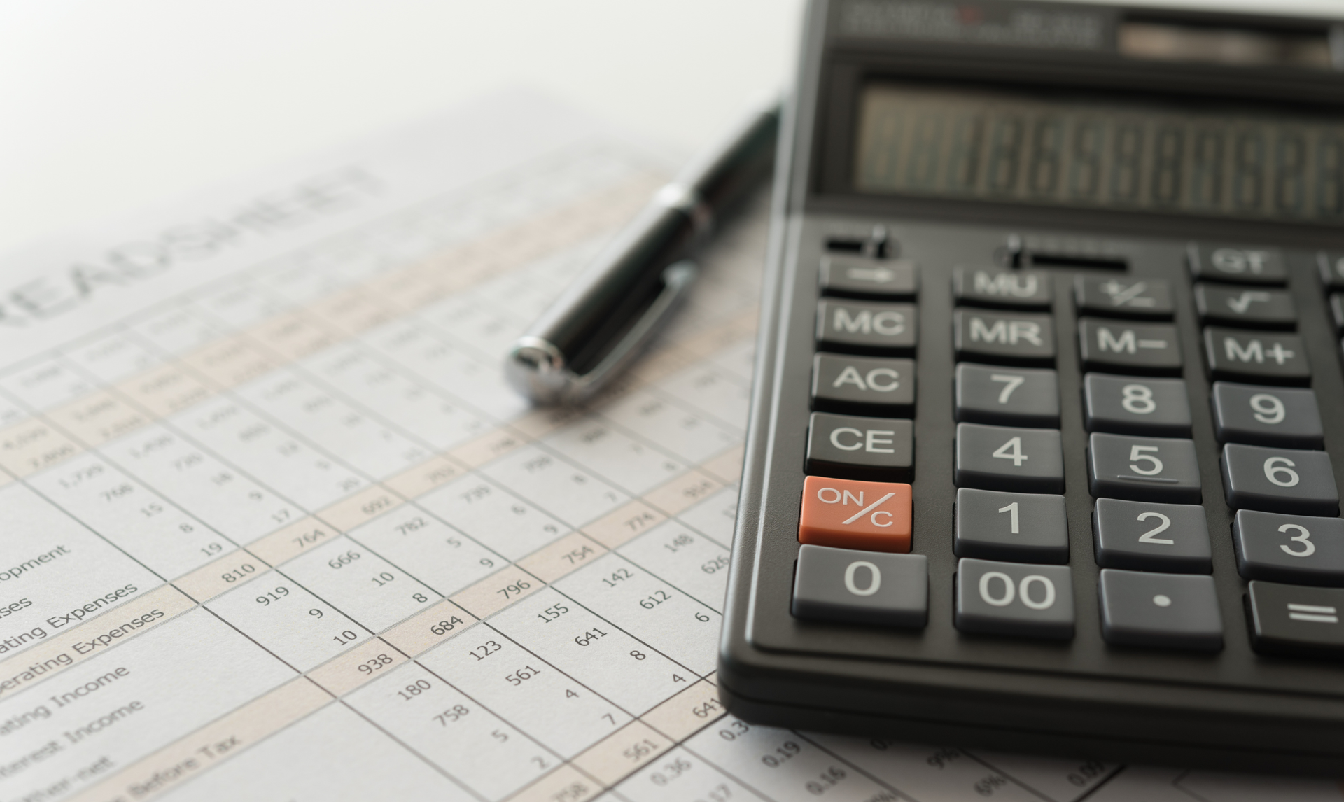 Person points at receipts with calculator, budgeting expenses on a white desk.