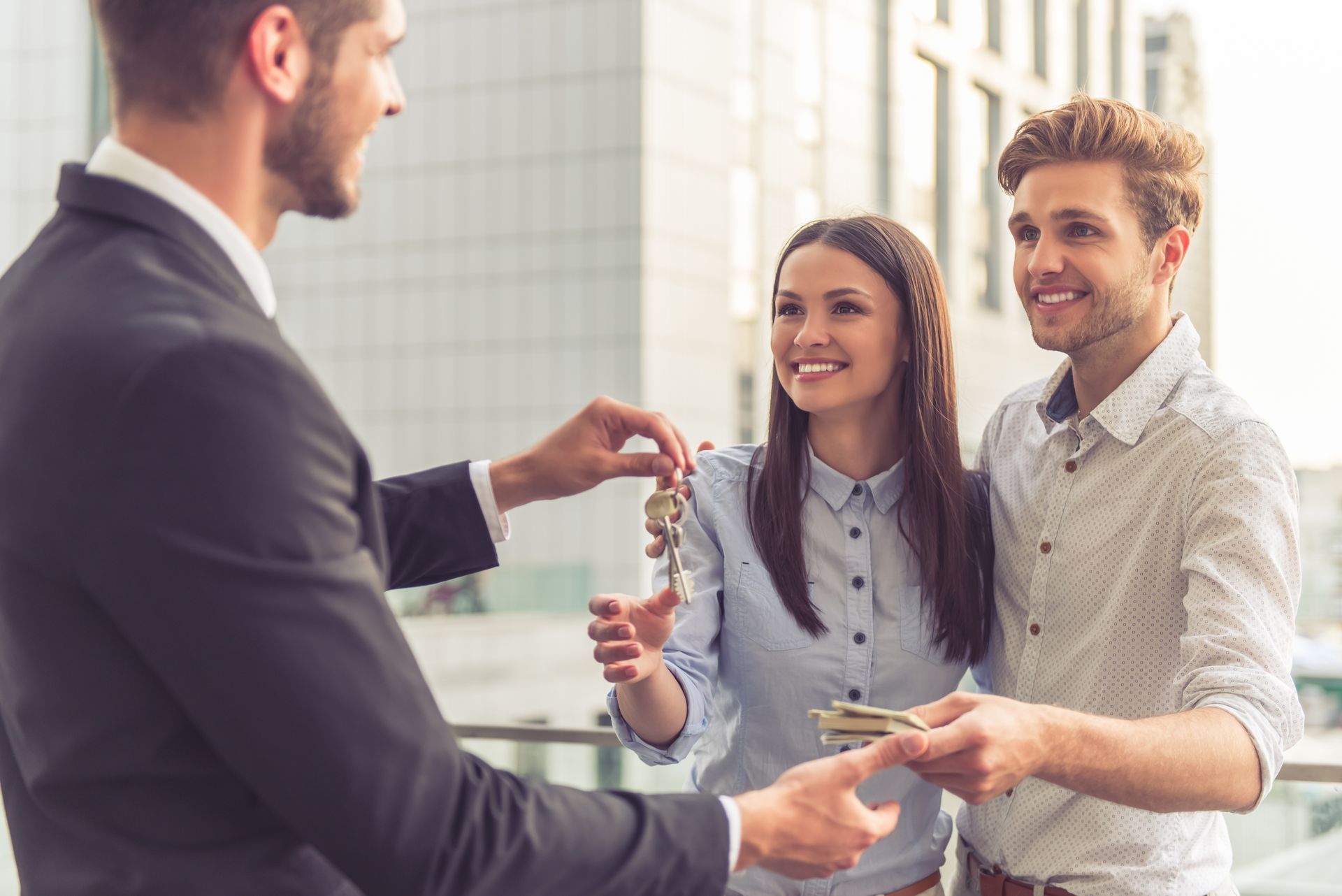 A male realtor gives a set of keys to a smiling couple. A male realtor gives a set of keys to a smiling couple.