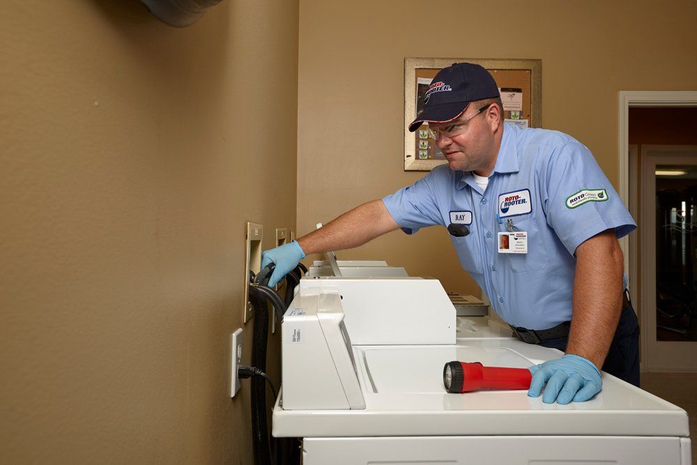 A man in a blue shirt is working on a washing machine