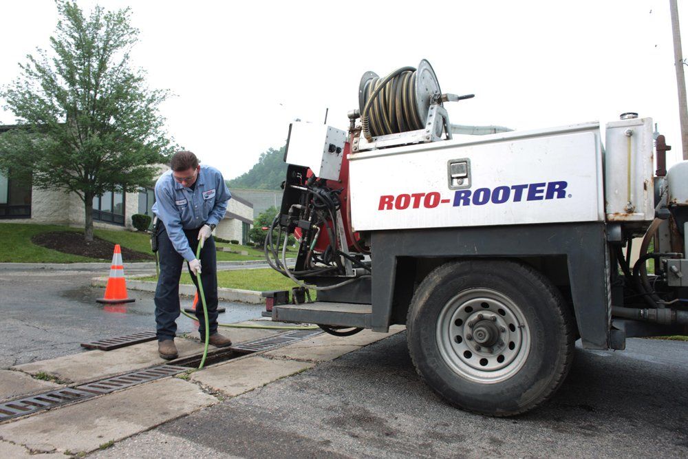 A man is standing next to a roto-rooter truck