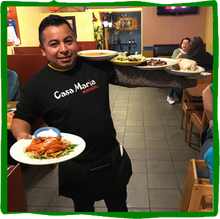 a man wearing a casa maria shirt is holding plates of food