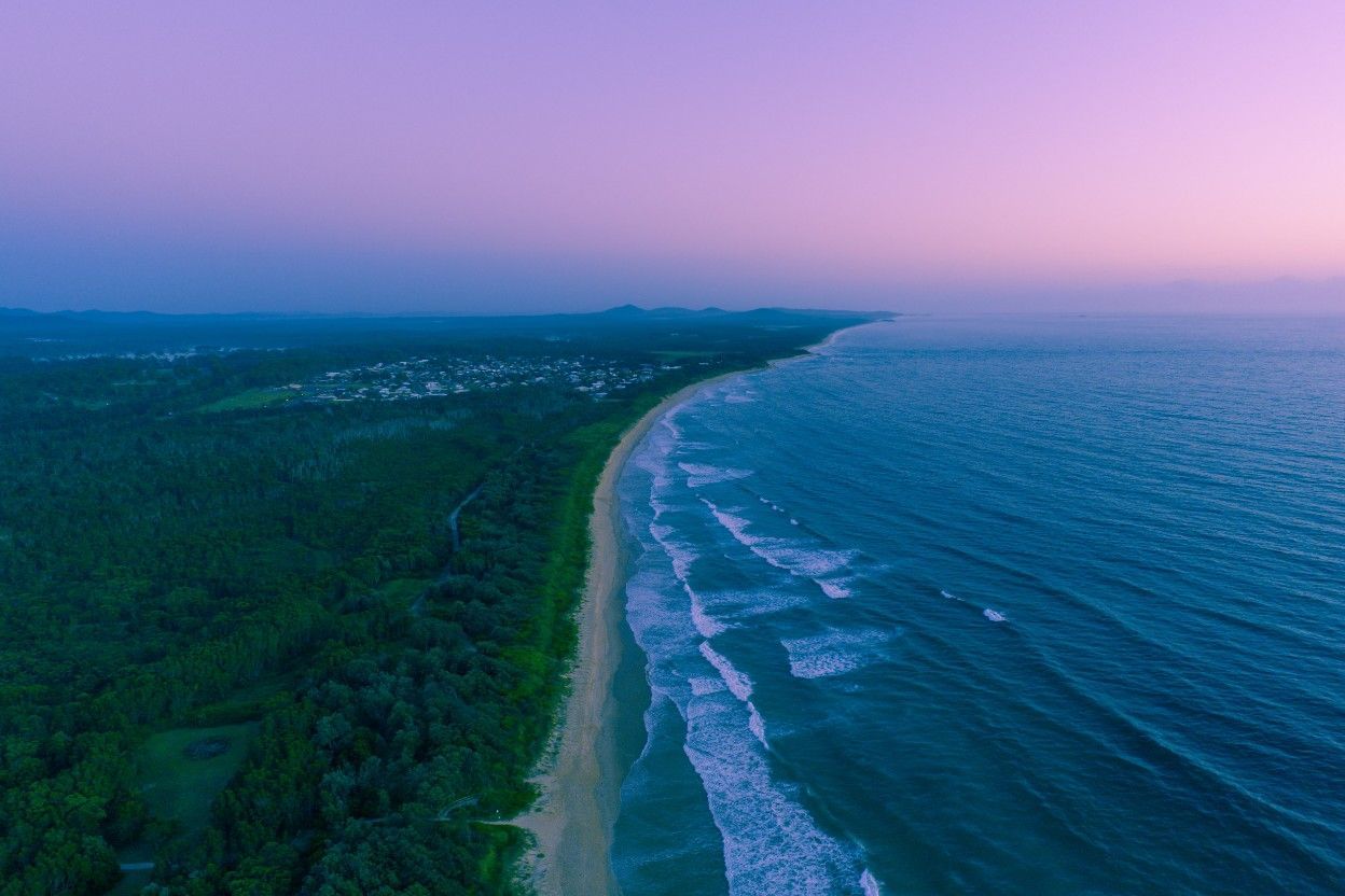 An Aerial View of a Beach and Ocean at Sunset — Coffs Coast Plumbing in Corindi Beach, NSW