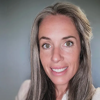A woman with long gray hair is smiling for the camera.