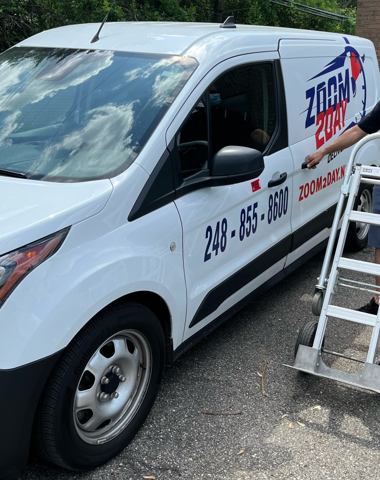 White Zoom Boat van with phone number, person opening door, parked outdoors. White Zoom Boat van with phone number, person opening door, parked outdoors.