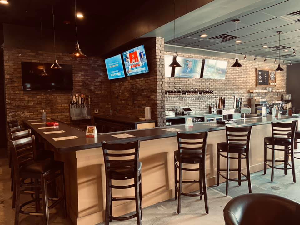 A restaurant with a long bar and chairs.