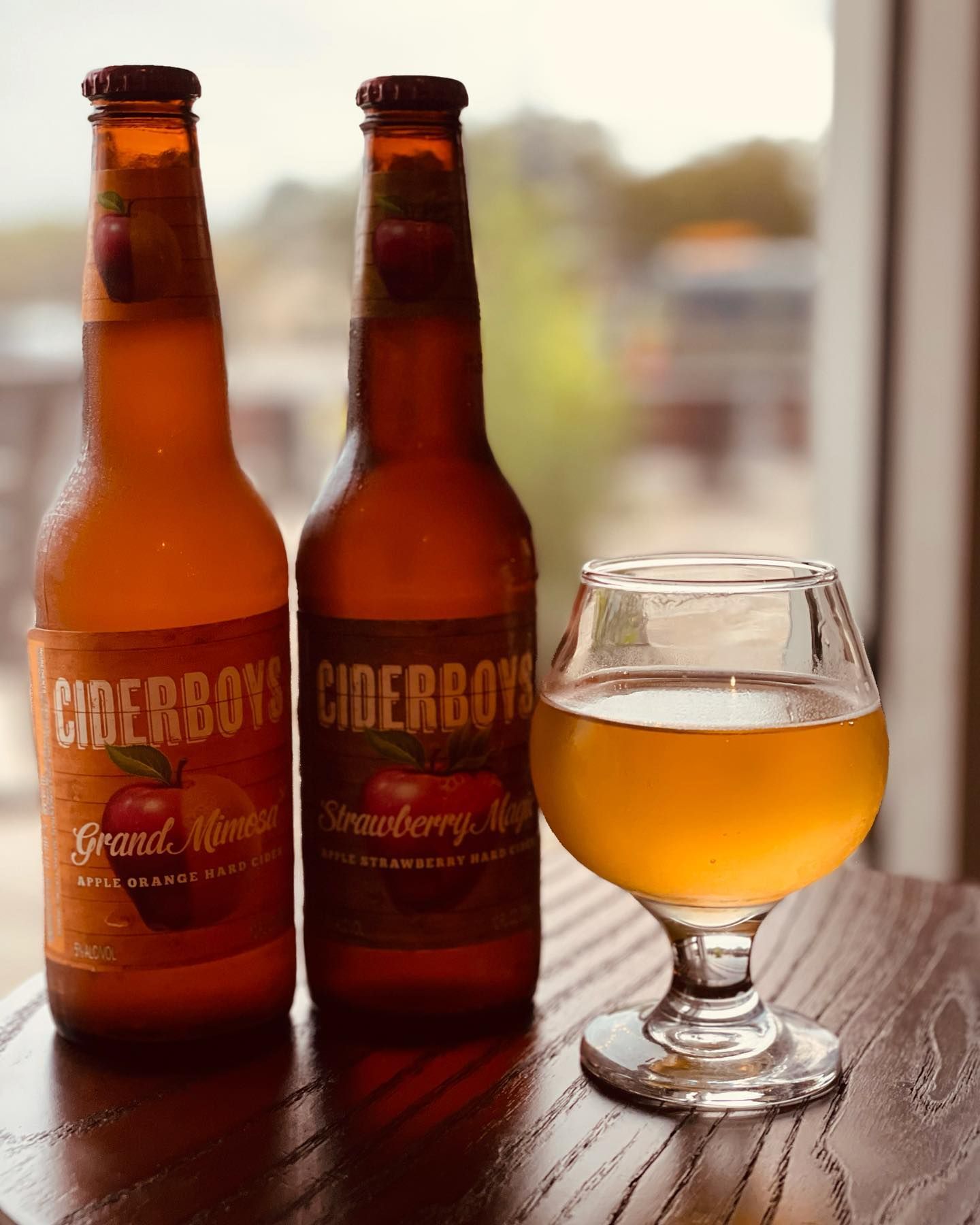 Two bottles of cider and a glass of cider on a table