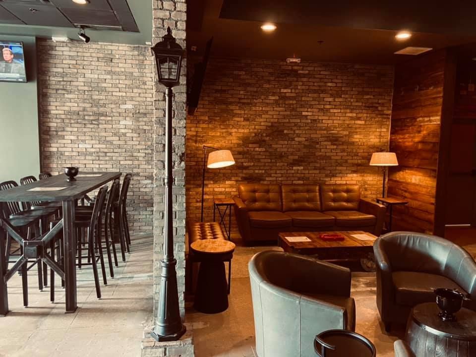 A living room with a brick wall , chairs , a table and a lamp post.