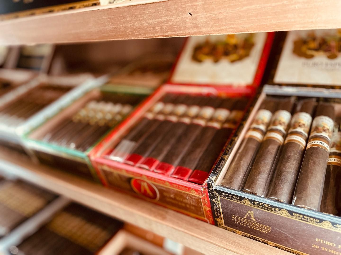 Boxes of cigars are lined up on a wooden shelf.