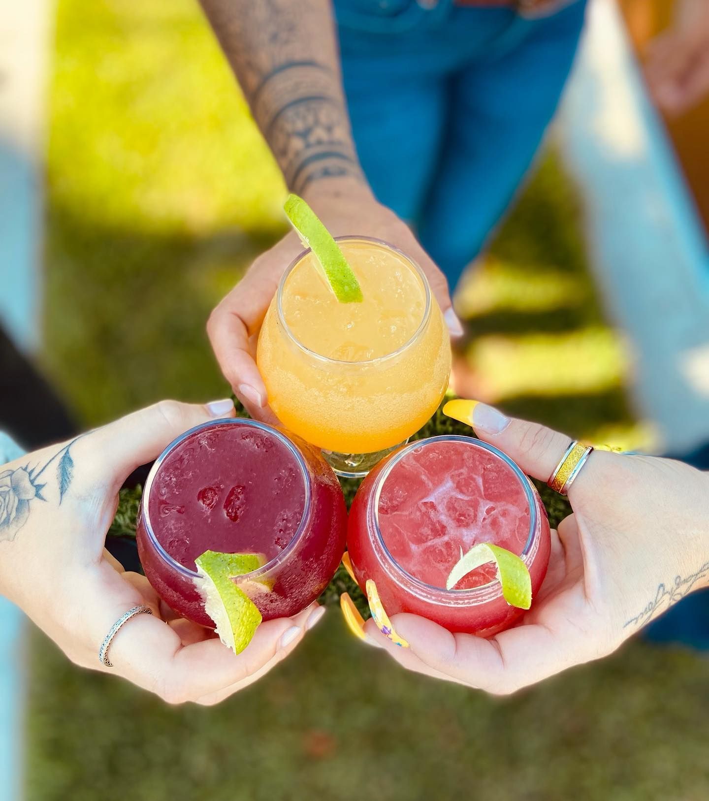 Three people are holding three different colored drinks in their hands.