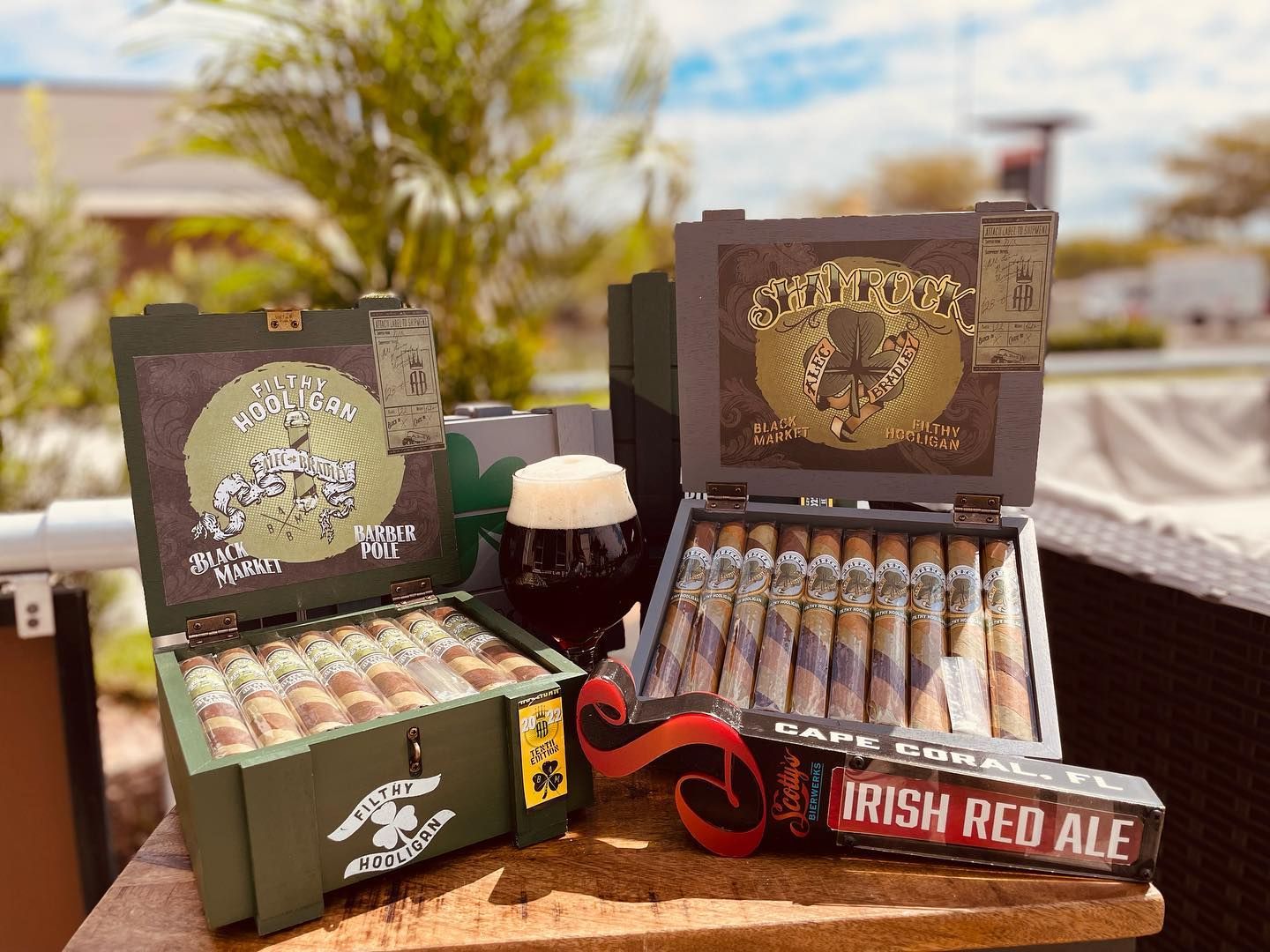 Two boxes of cigars and a box of irish red ale are sitting on a table.