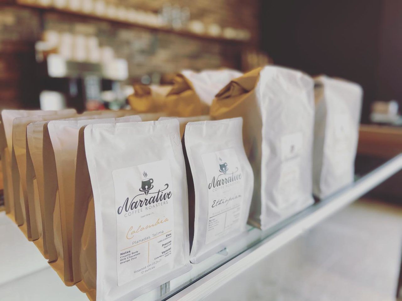 Several bags of coffee are lined up on a shelf.