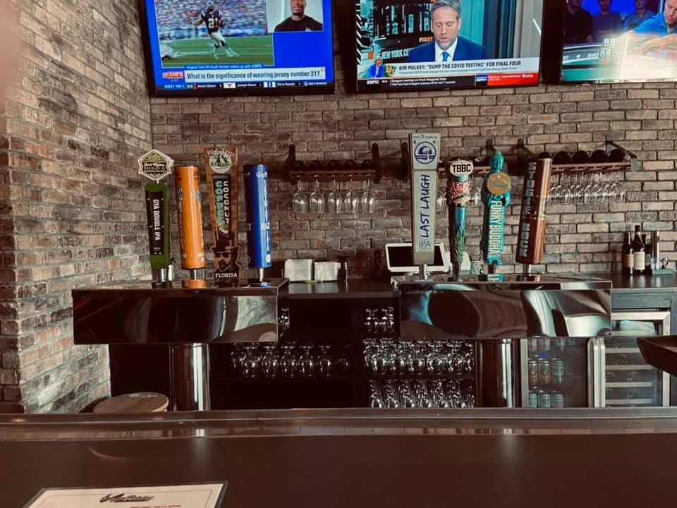 A bar with a lot of beer taps and televisions on the wall.