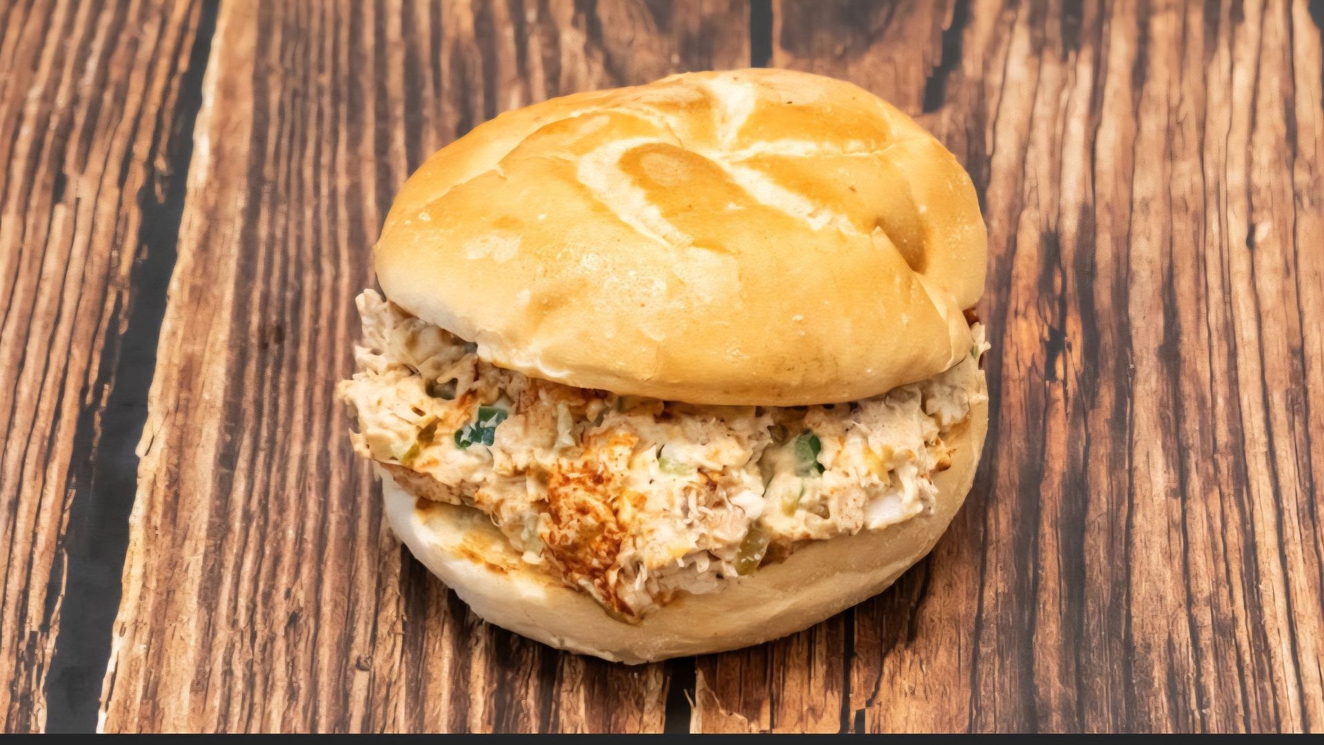 Chicken salad sandwich on a brown, wooden table.
