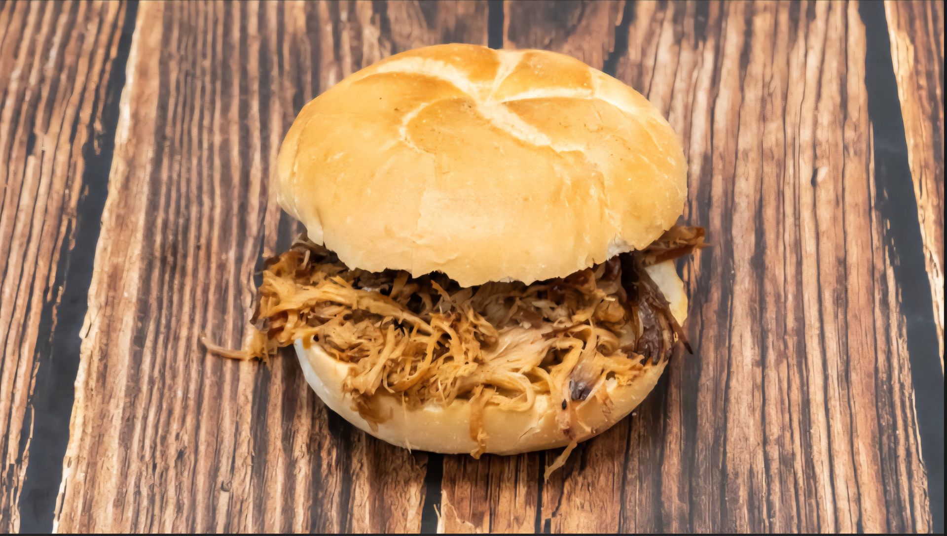 Pulled pork sandwich on a kaiser roll, on a wooden table.