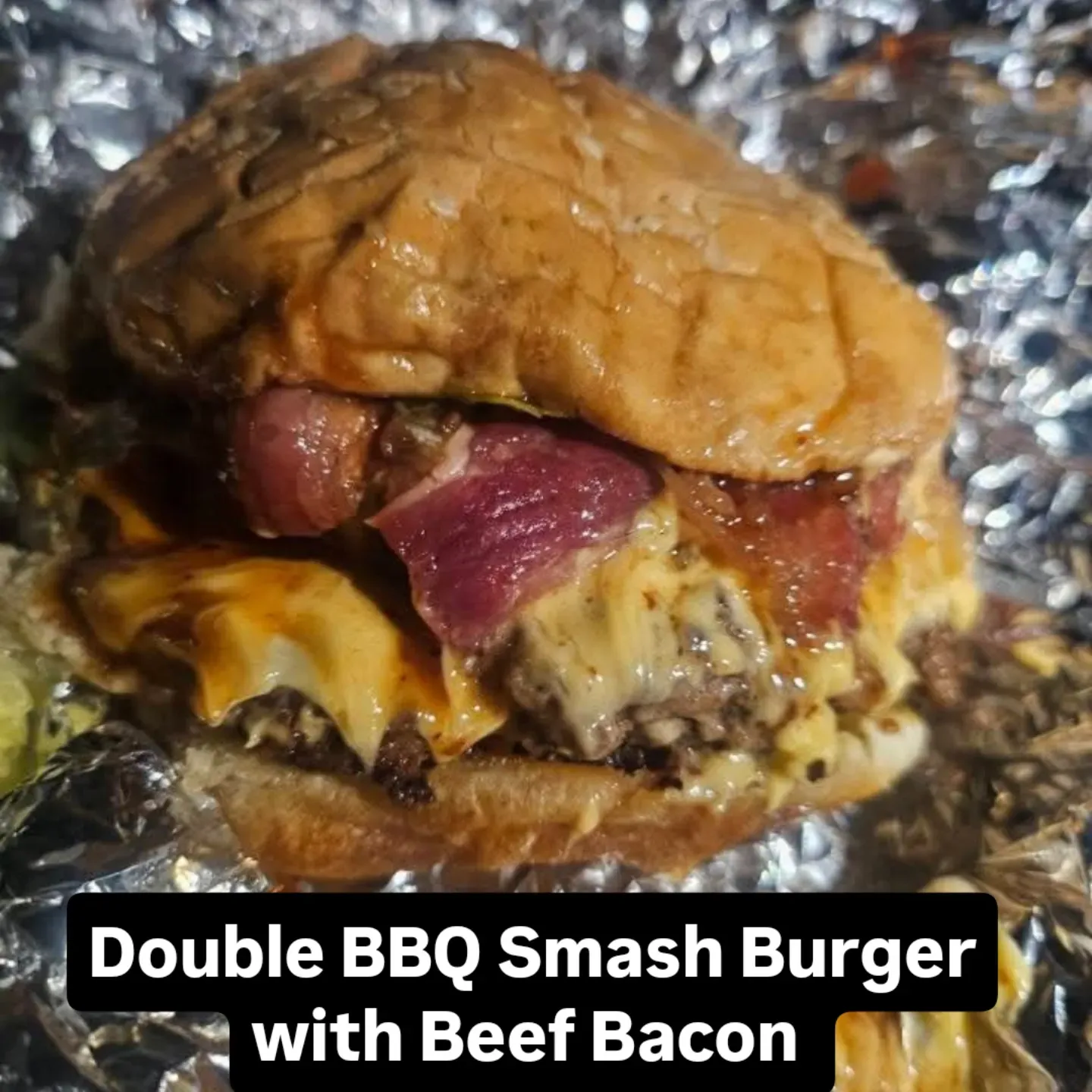 Double BBQ smash burger with beef bacon on foil.