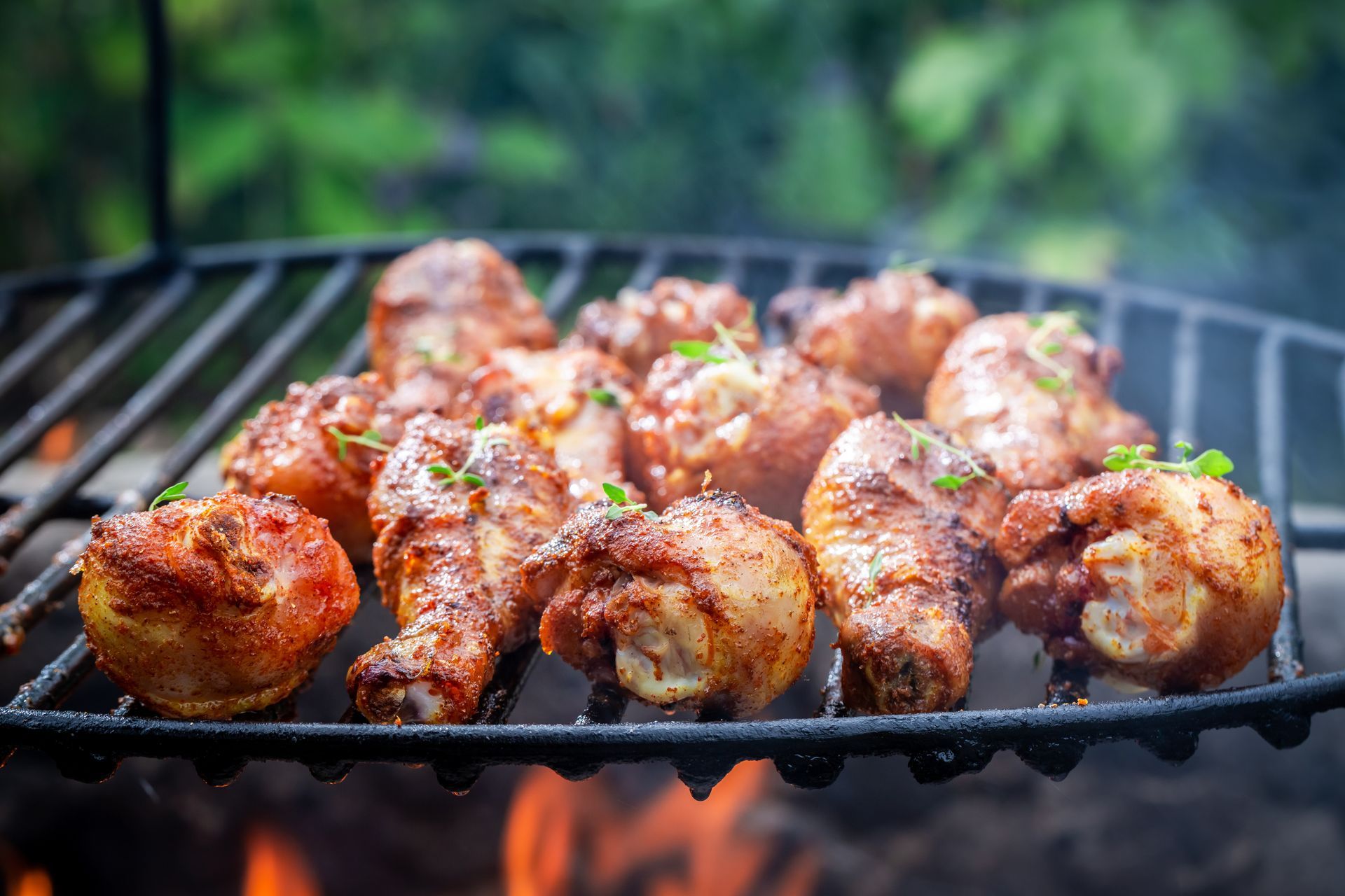 Grilled chicken drumsticks on a hot grill with flames.