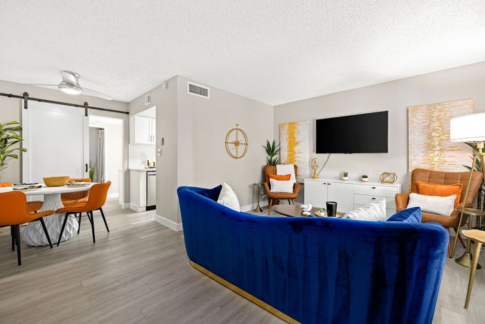 A room with tables and chairs and a television on the wall.