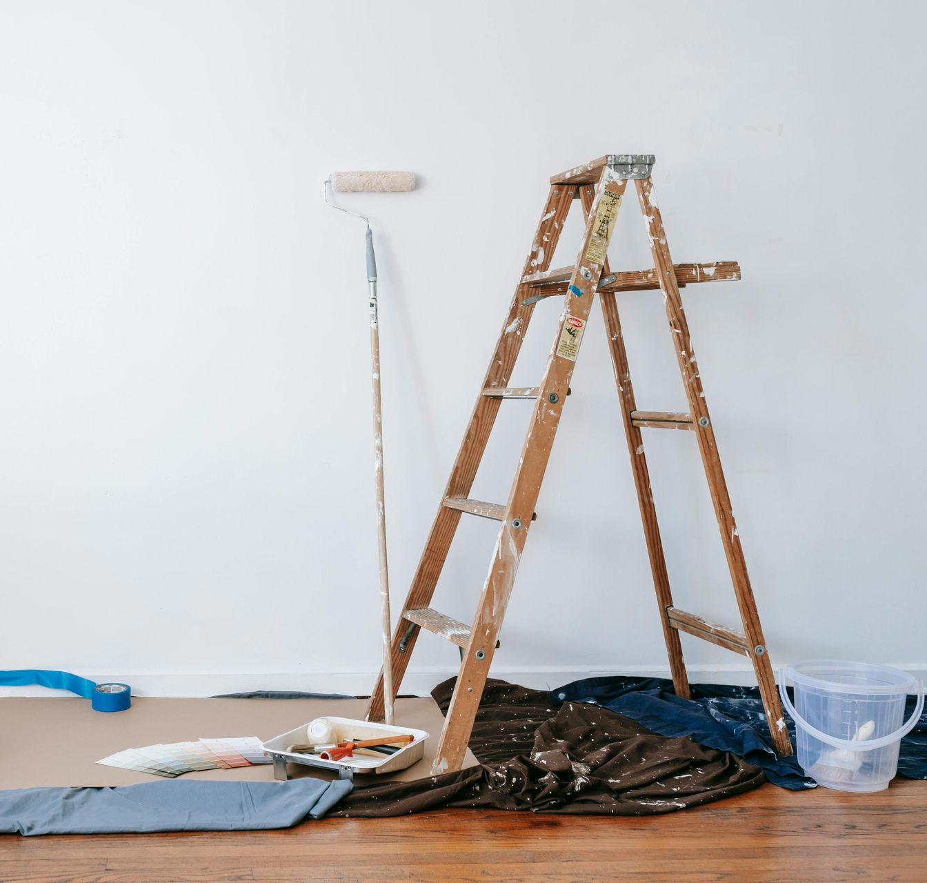 Ladder and paint supplies next to a white wall during painting project.
