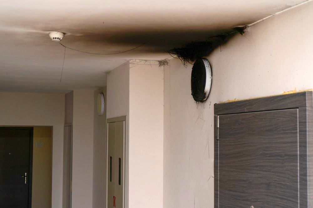 Smoke damage on a ceiling and wall near a ventilation opening, suggesting a fire.