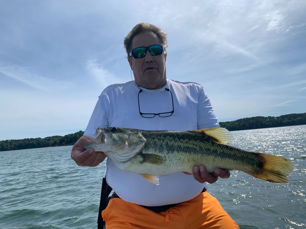 A man is holding a large bass on a boat.
