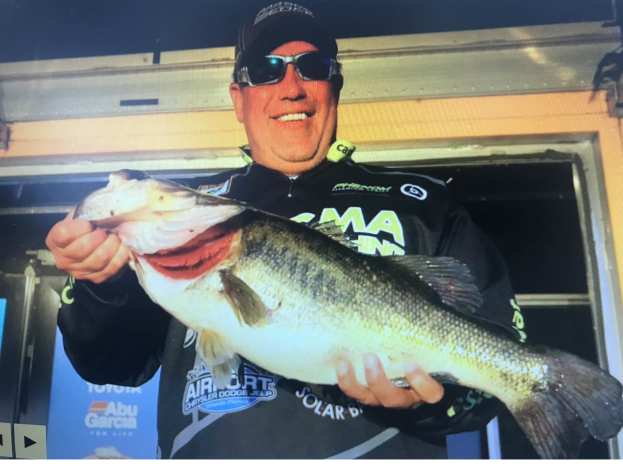A man wearing sunglasses is holding a large fish