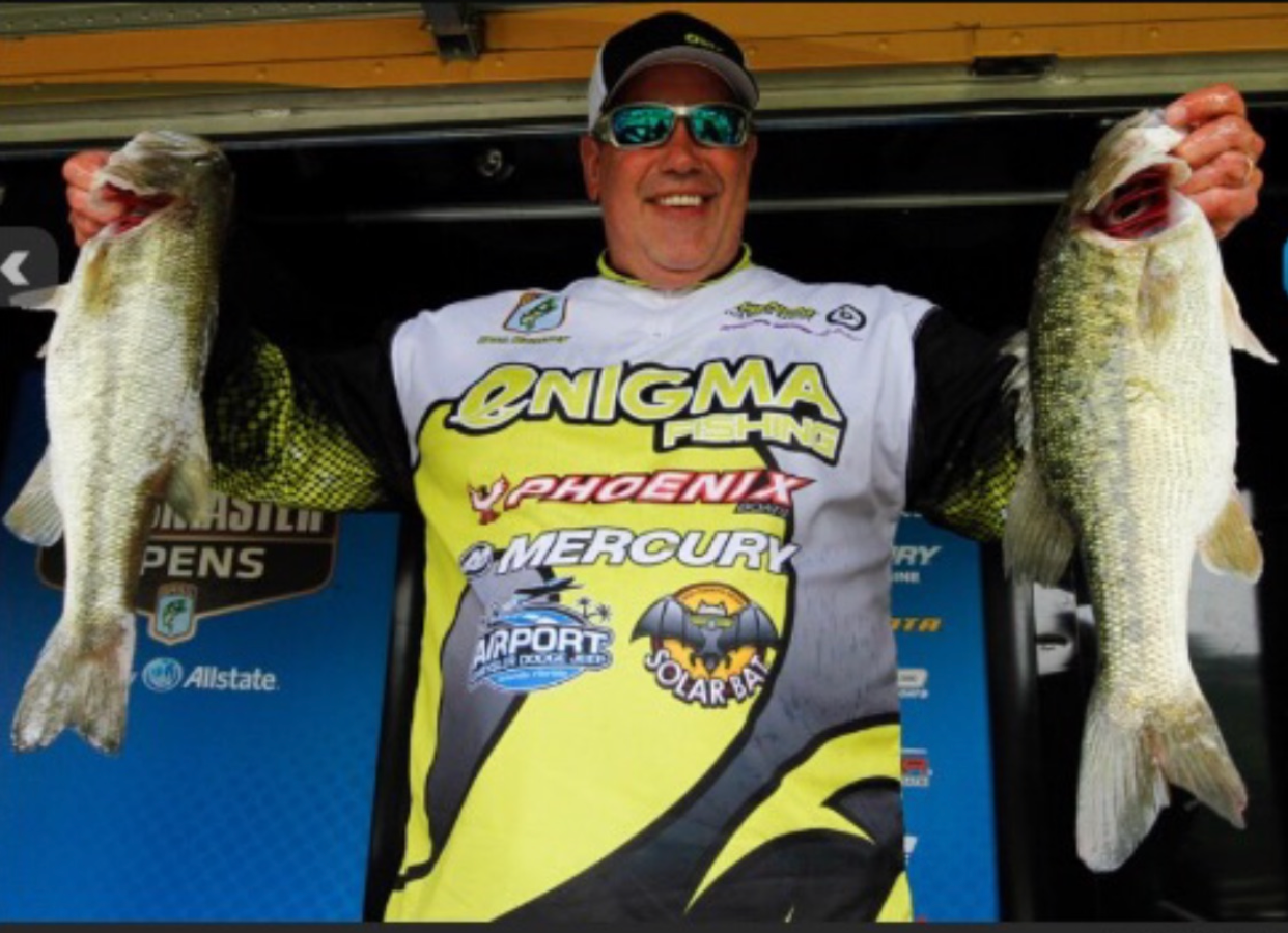 A man in an enigma phoenix shirt holds two fish