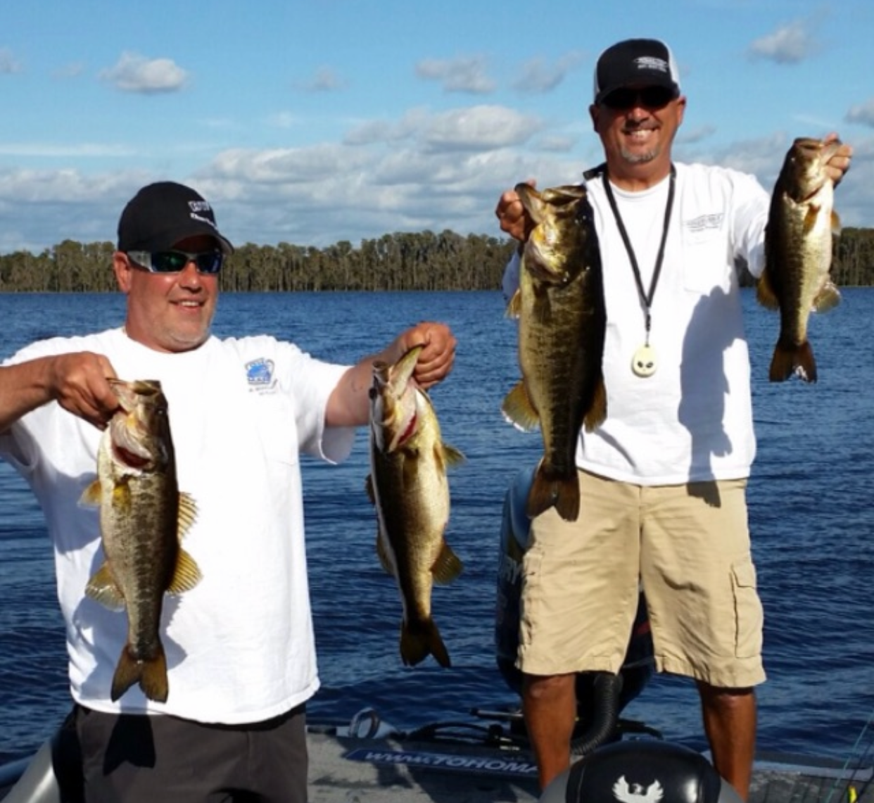 Two men on a boat holding up their fish