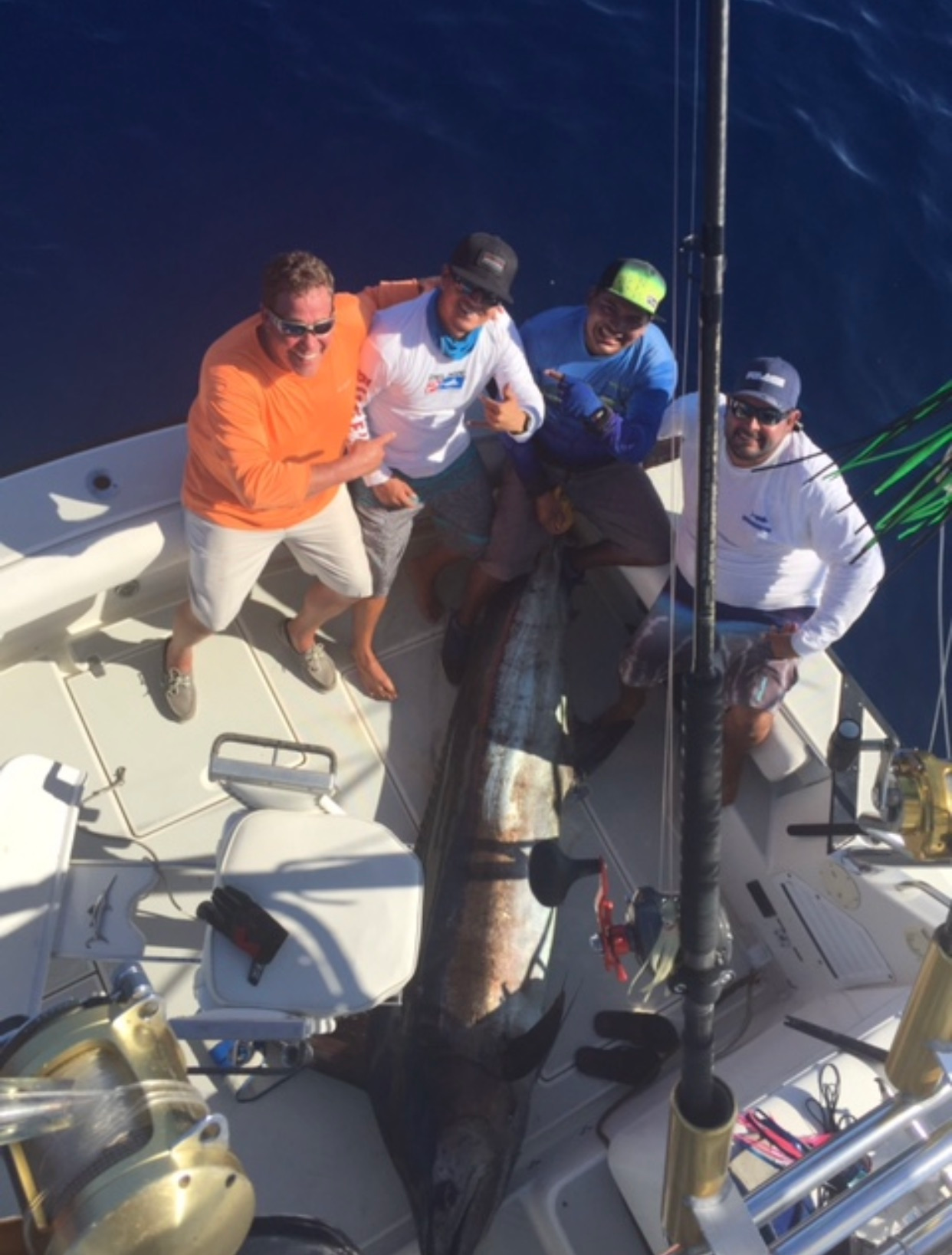 A group of men on a boat holding a large fish