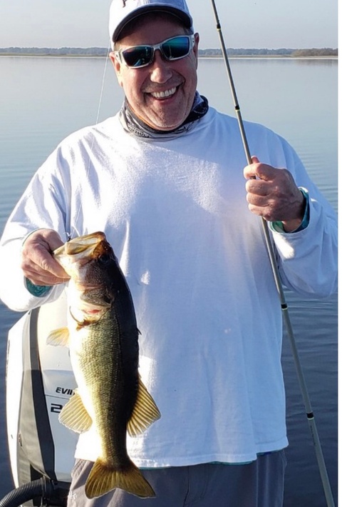 A man in a white shirt is holding a large fish in his hands.