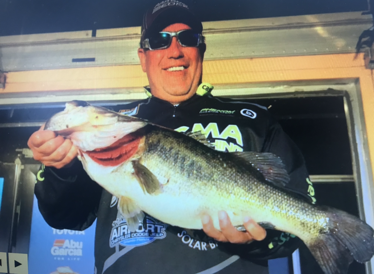 A man holding a large fish in front of a sign that says abu garcia
