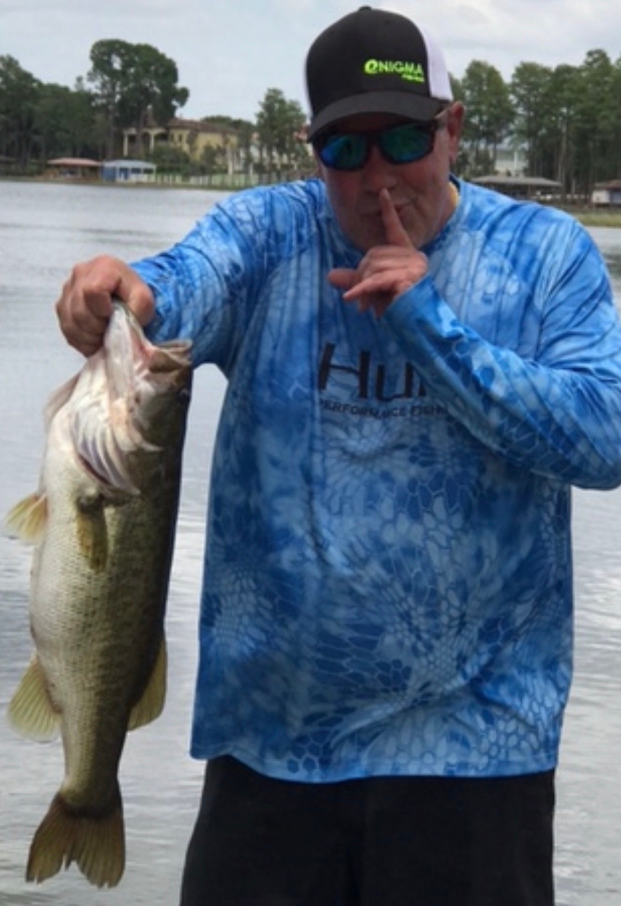 A man in a blue shirt is holding a large fish