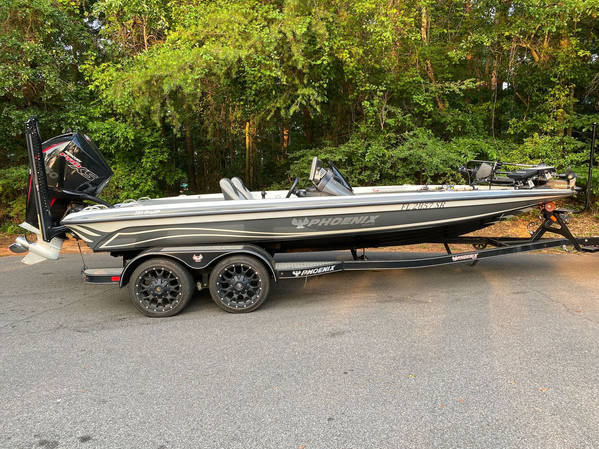 A fishing boat is parked on the side of the road on a trailer.