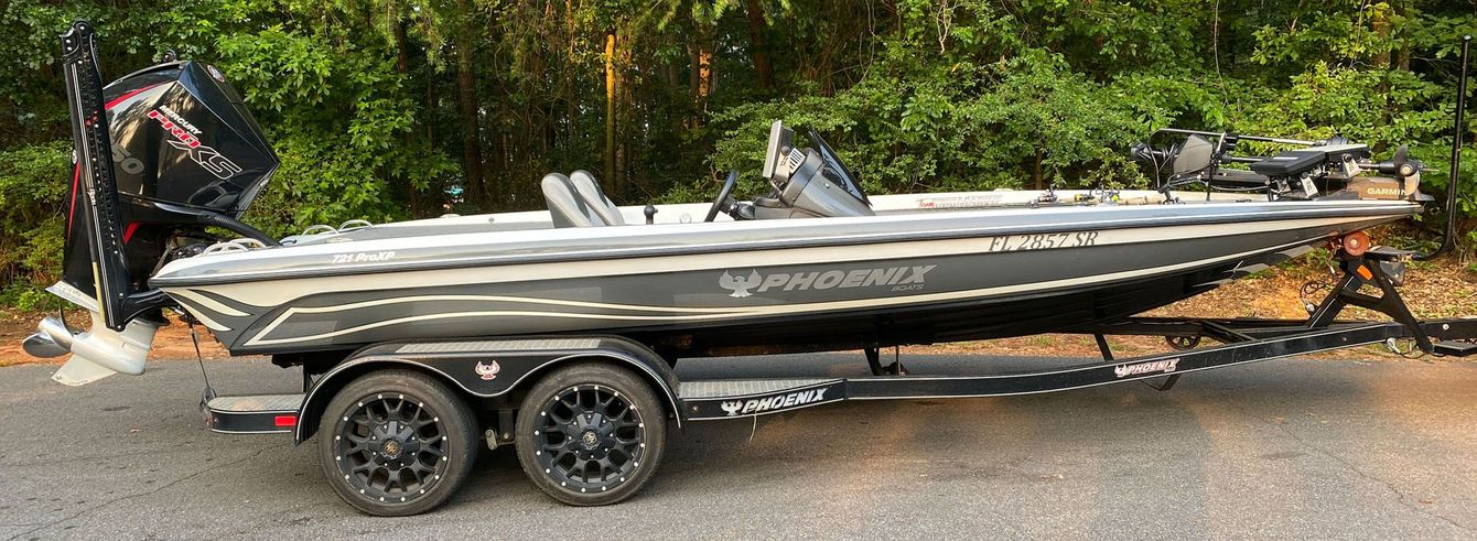 A fishing boat on a trailer is parked on the side of the road.