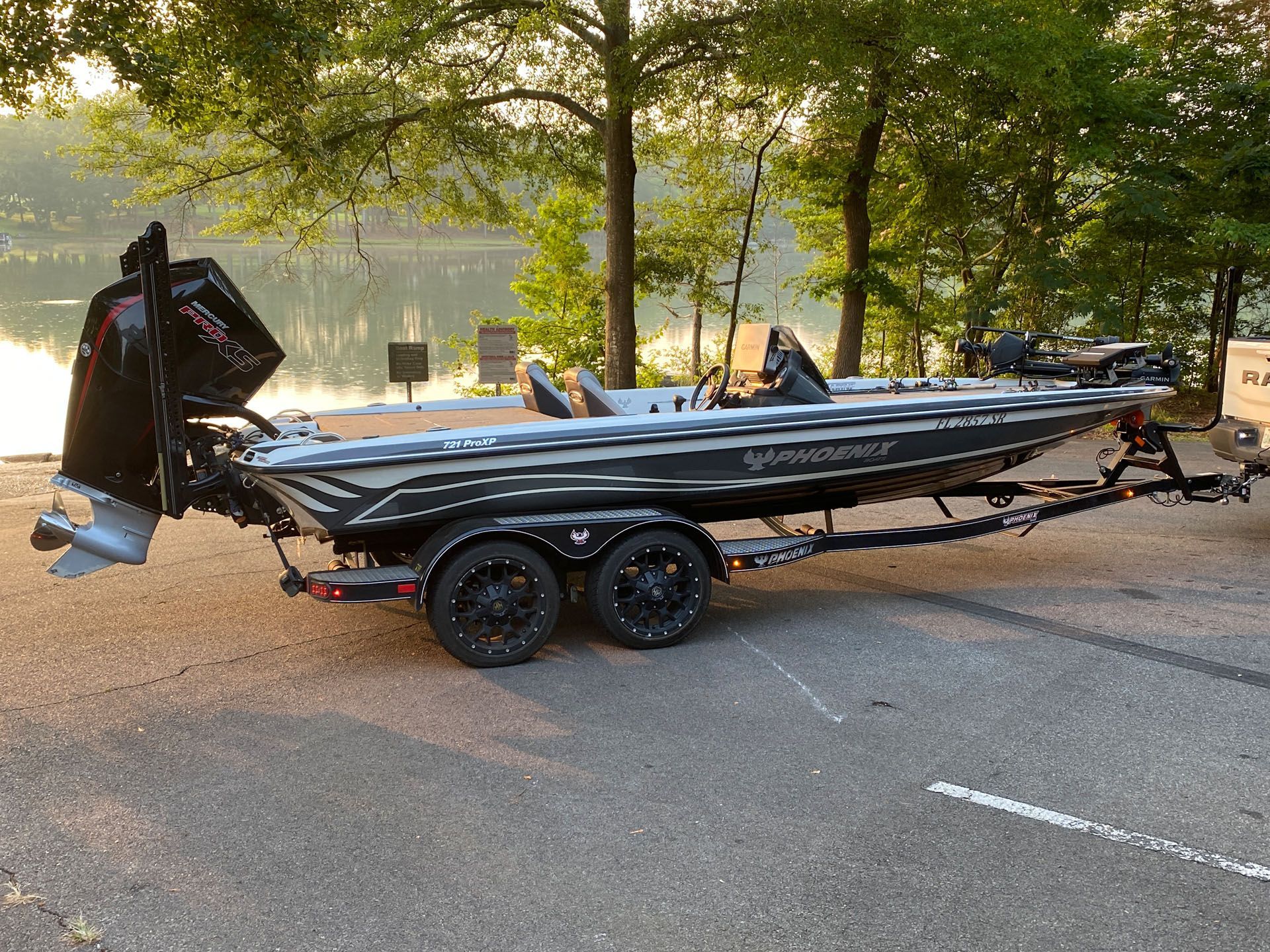 A boat is parked on a trailer next to a lake.