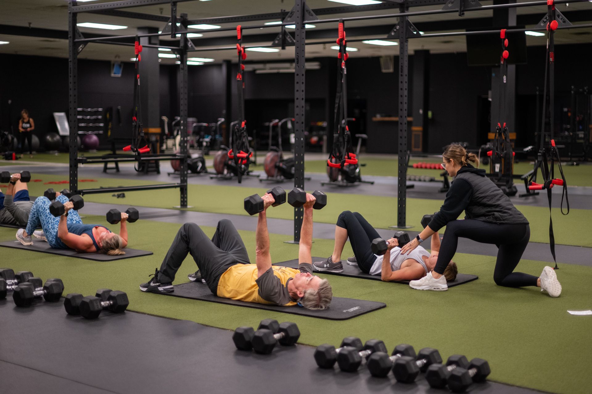 A group of people are doing exercises with dumbbells in a gym.